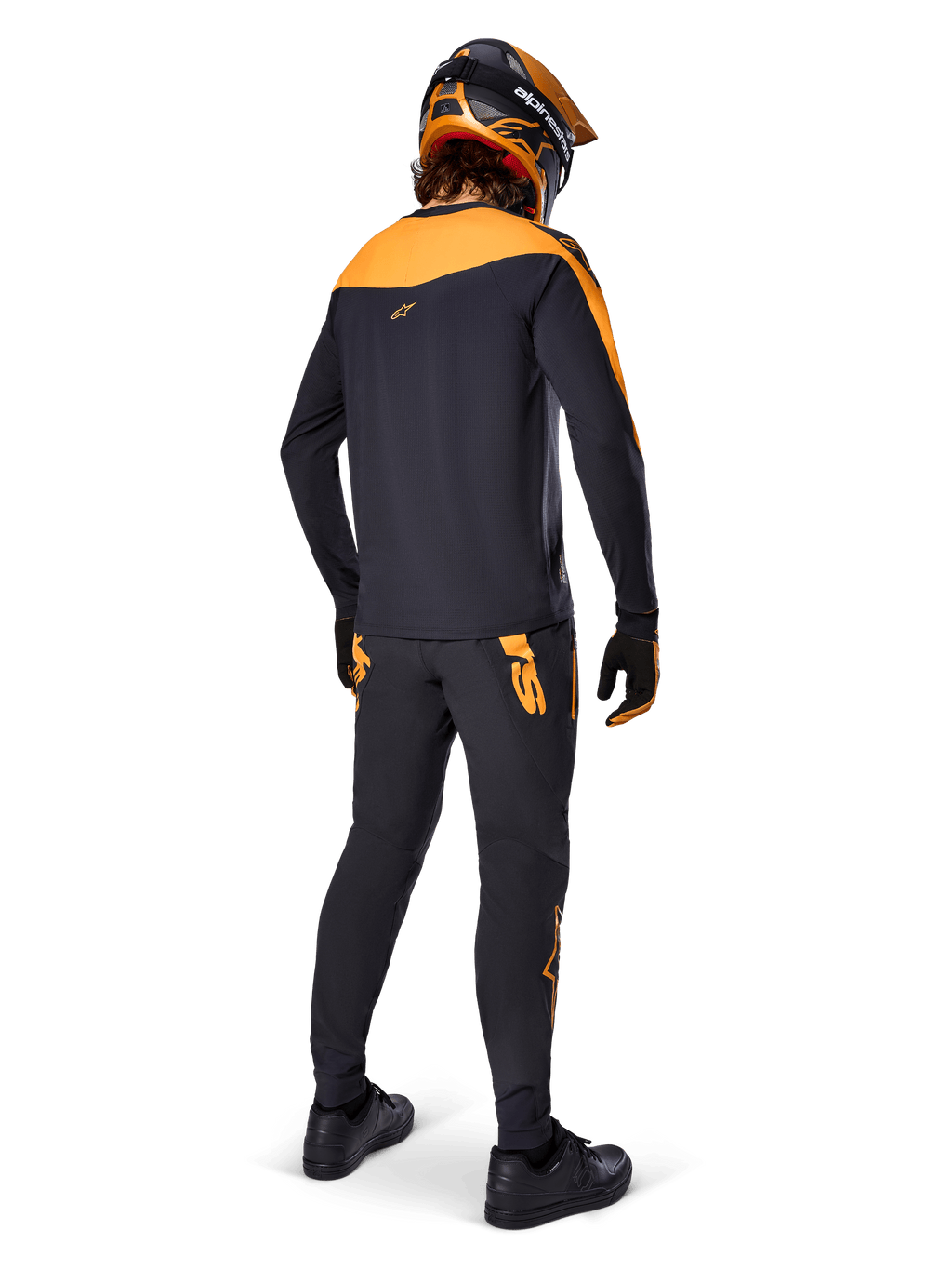 Koszulka A-Supra Race Jersey z długim rękawem, czarno-pomarańczowa, widok z tyłu na rowerzystę w pasujących spodniach MTB, pomarańczowo-czarnym kasku i rękawicach, odzież wyczynowa do wyścigów MTB