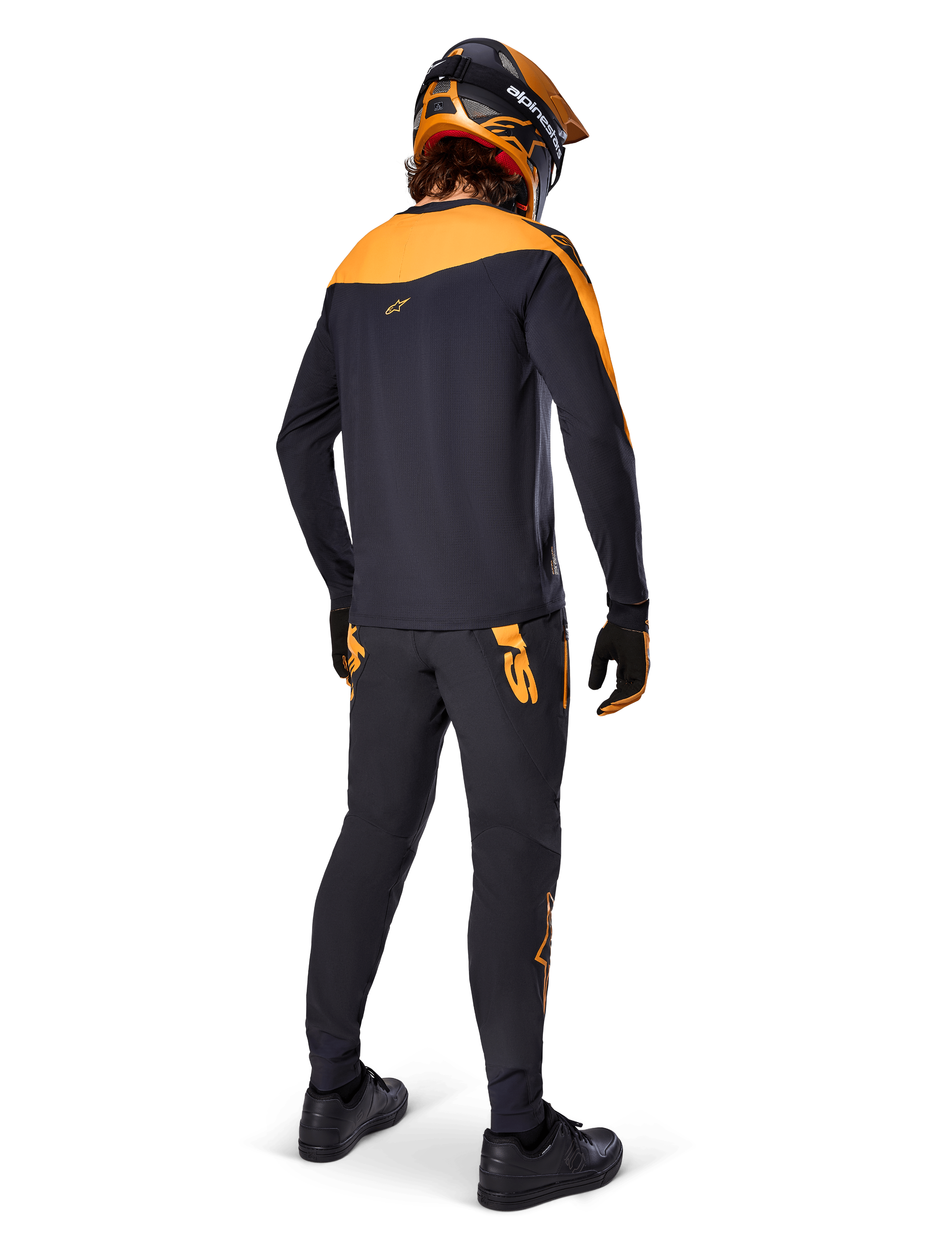 Koszulka A-Supra Race Jersey z długim rękawem, czarno-pomarańczowa, widok z tyłu na rowerzystę w pasujących spodniach MTB, pomarańczowo-czarnym kasku i rękawicach, odzież wyczynowa do wyścigów MTB