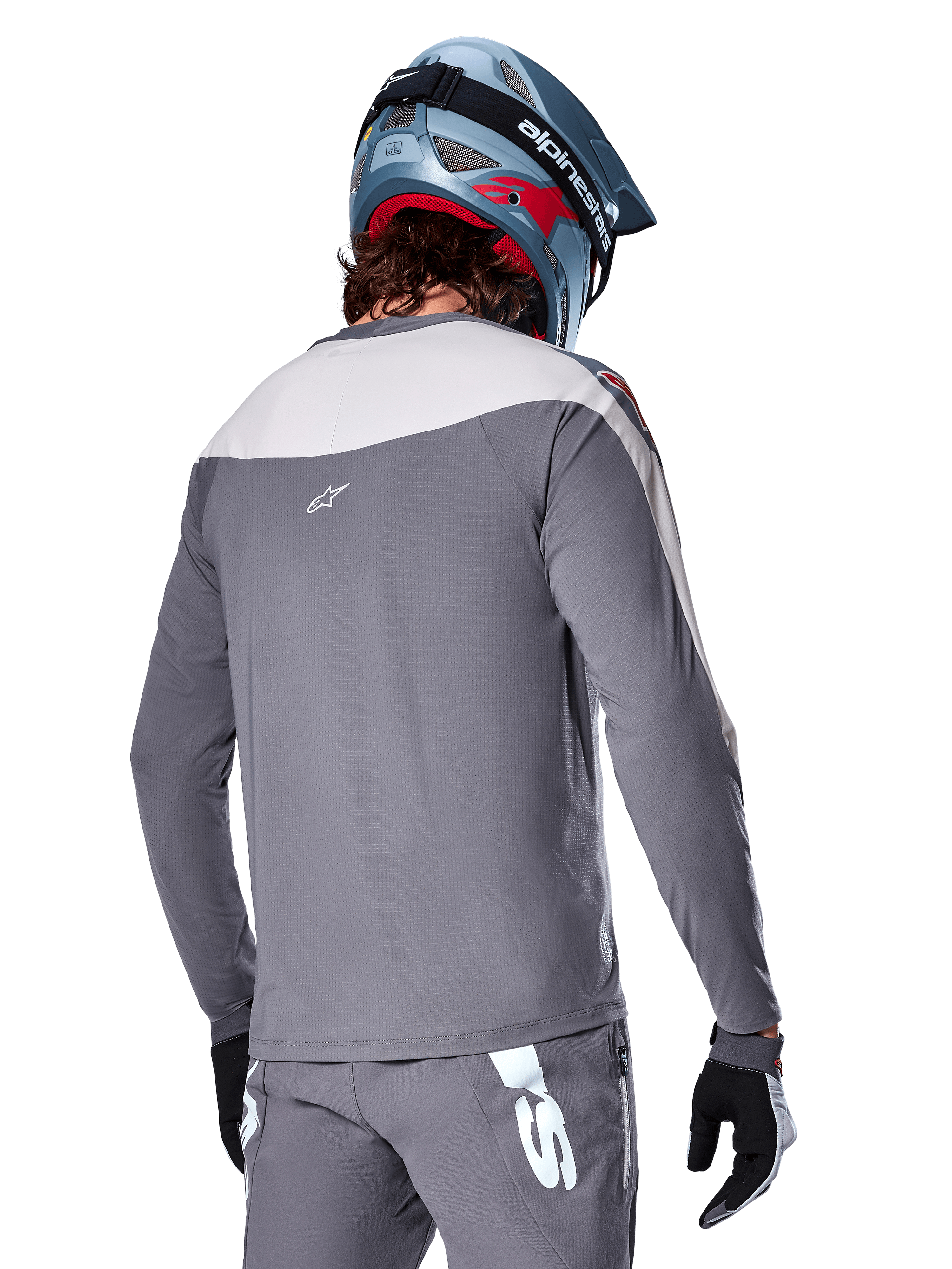 Koszulka Alpinestars A-Supra Race, koszulka MTB z długim rękawem w kolorze ciemnoszarym i jasnoszarym, widok z tyłu ukazujący sportowy krój i logo Astar, noszona z pasującymi szarymi spodniami i niebieskim kaskiem rowerowym, zaprojektowana do jazdy terenowej MTB