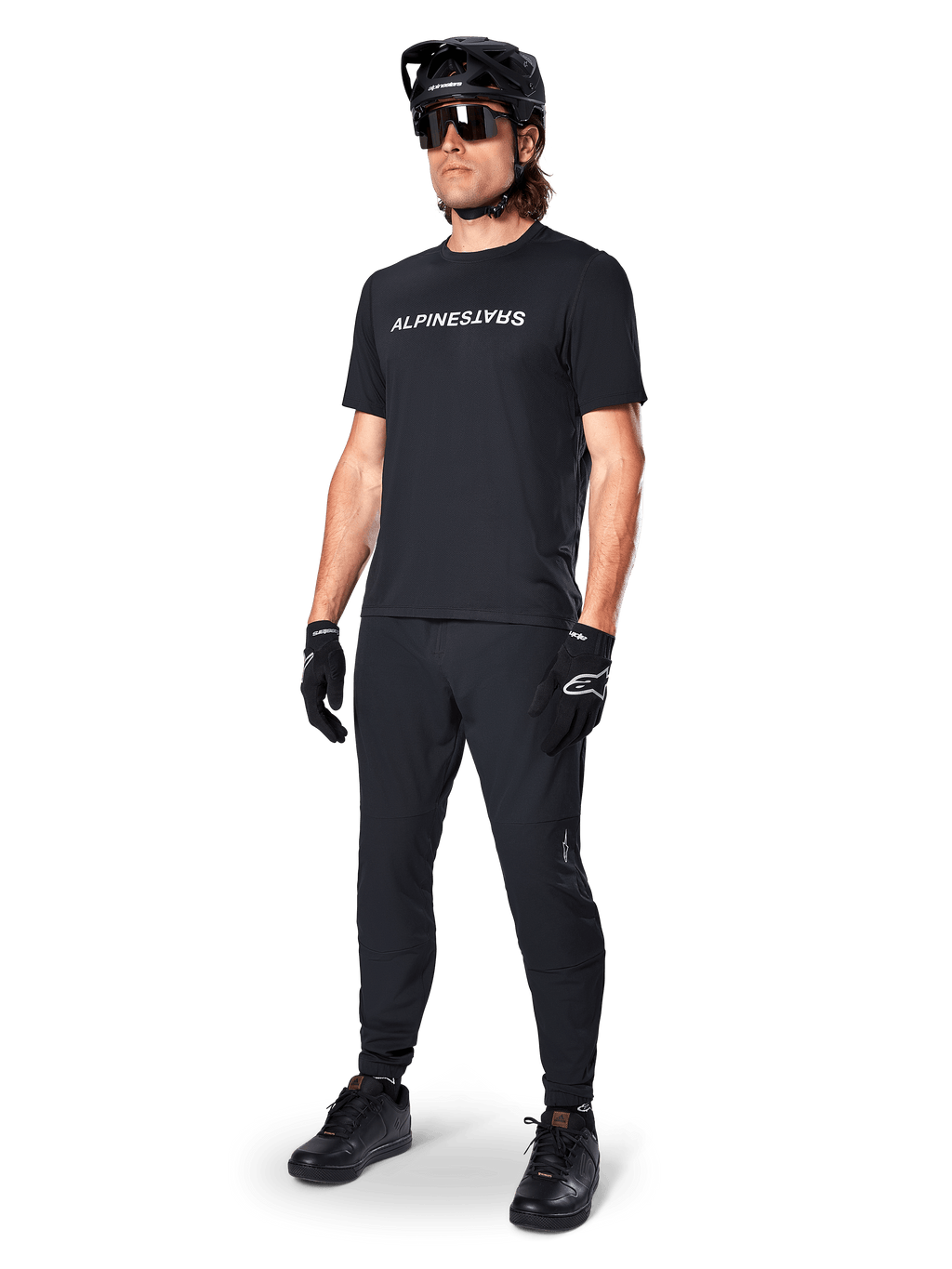 Alpinestars A-Dura Switch Short Sleeve Jersey, czarna, noszona przez modela z dopasowanymi czarnymi spodniami MTB, kaskiem i rękawicami, z białym napisem Alpinestars na piersi, techniczna odzież do kolarstwa górskiego