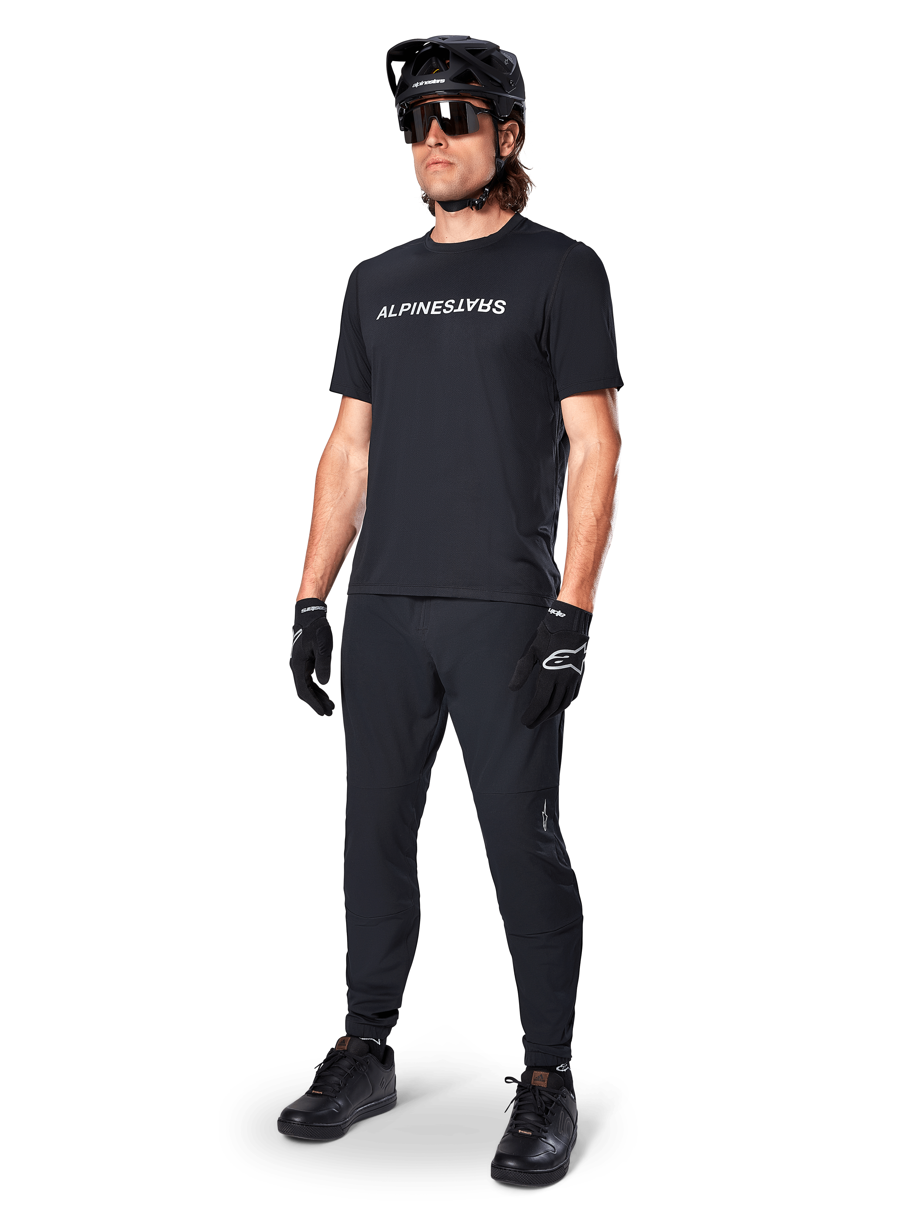 Alpinestars A-Dura Switch Short Sleeve Jersey, czarna, noszona przez modela z dopasowanymi czarnymi spodniami MTB, kaskiem i rękawicami, z białym napisem Alpinestars na piersi, techniczna odzież do kolarstwa górskiego