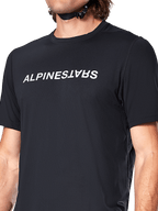 Alpinestars A-Dura Switch Short Sleeve Jersey, czarna koszulka z krótkim rękawem, duże białe logo nadrukowane na klatce piersiowej, tekstura materiału żakardowego, zbliżenie z przodu