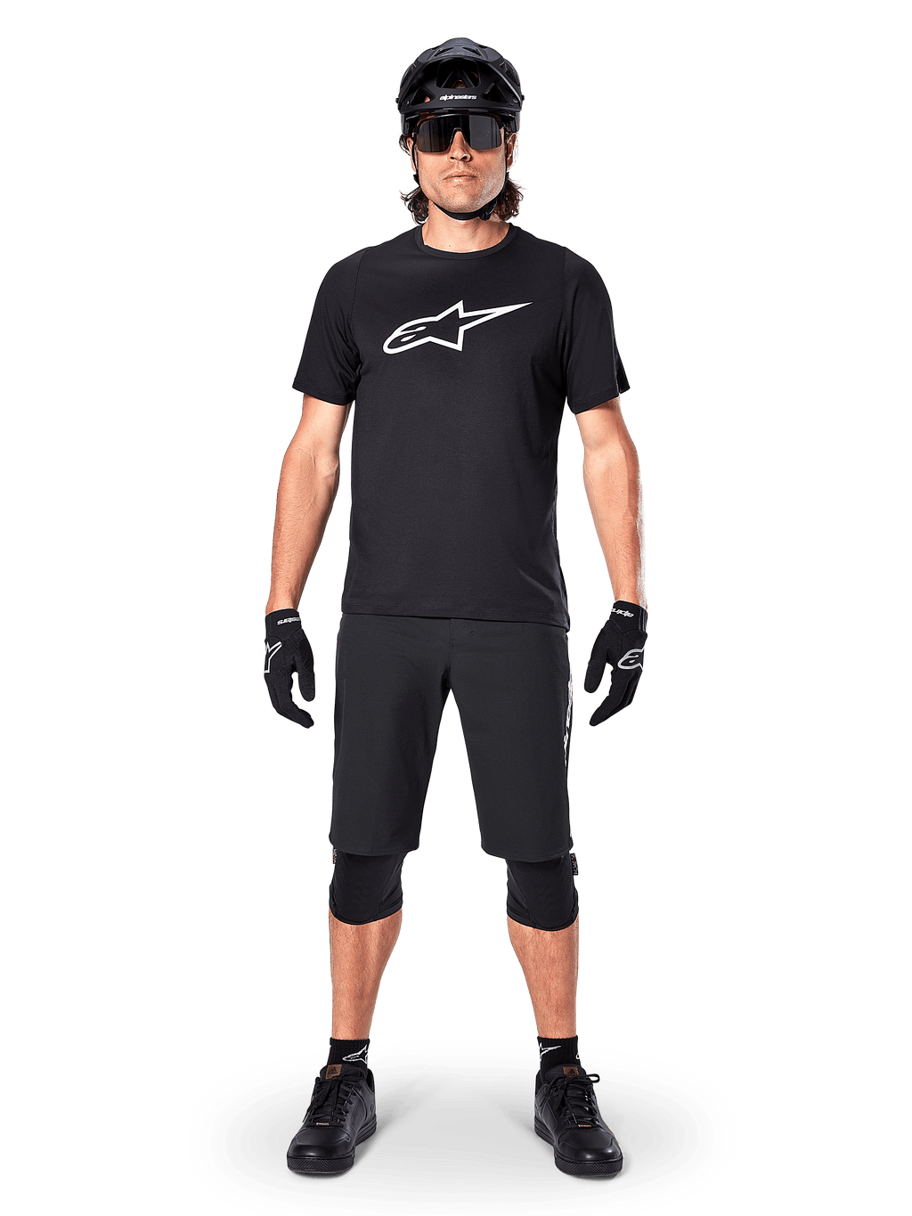 Koszulka z krótkim rękawem Alpinestars A-Dura Dri Oscar, Black Reflective, noszona z dopasowanymi czarnymi szortami MTB, rękawiczkami, nakolannikami i kaskiem, z dużym białym logo Alpinestars na klatce piersiowej, kompletny strój do jazdy na rowerze górskim