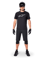 Koszulka z krótkim rękawem Alpinestars A-Dura Dri Oscar, Black Reflective, noszona z dopasowanymi czarnymi szortami MTB, rękawiczkami, nakolannikami i kaskiem, z dużym białym logo Alpinestars na klatce piersiowej, kompletny strój do jazdy na rowerze górskim