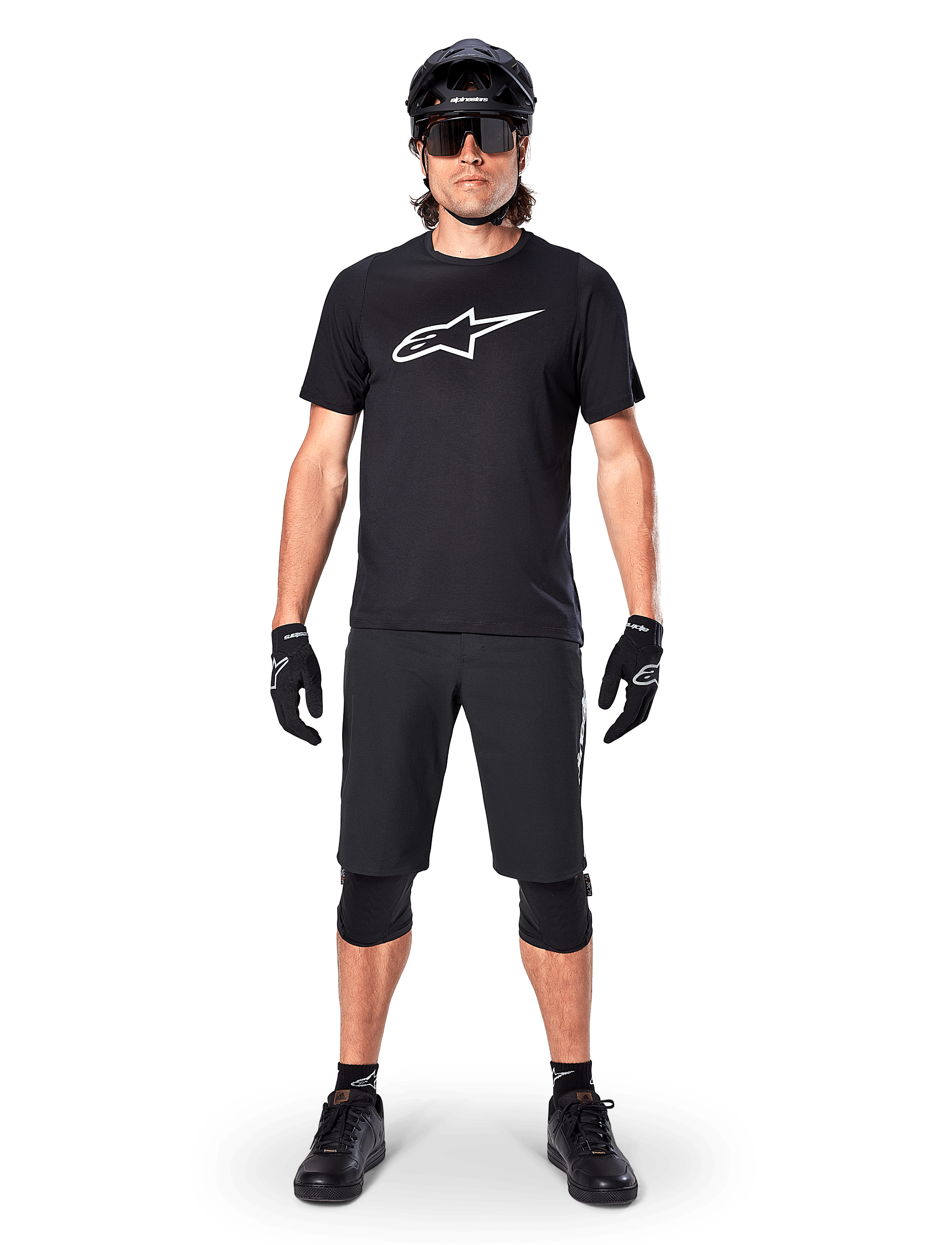 Koszulka z krótkim rękawem Alpinestars A-Dura Dri Oscar, Black Reflective, noszona z dopasowanymi czarnymi szortami MTB, rękawiczkami, nakolannikami i kaskiem, z dużym białym logo Alpinestars na klatce piersiowej, kompletny strój do jazdy na rowerze górskim