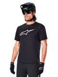 Alpinestars A-Dura Dri Oscar Jersey, koszulka rowerowa MTB z krótkim rękawem, czarna z białym logo, techniczny materiał odprowadzający wilgoć, noszona z czarnym kaskiem, okularami przeciwsłonecznymi i rękawiczkami