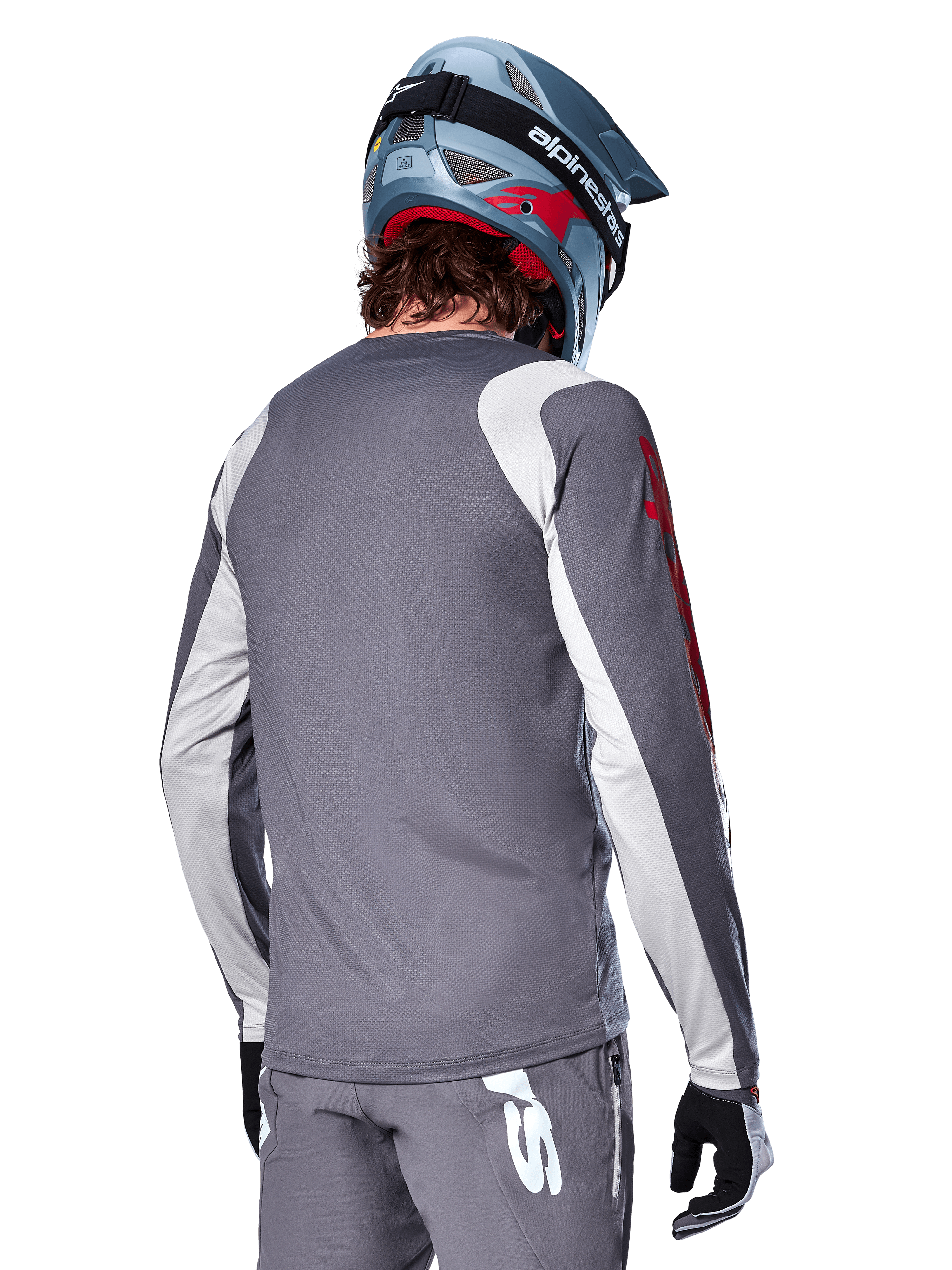 Koszulka Alpinestars A-Supra Astar z długim rękawem, ciemnoszara z jasnoszarymi panelami na ramionach i rękawach, widok z tyłu na rowerzystę w niebieskim kasku full-face i szarych spodniach, sportowa odzież rowerowa MTB