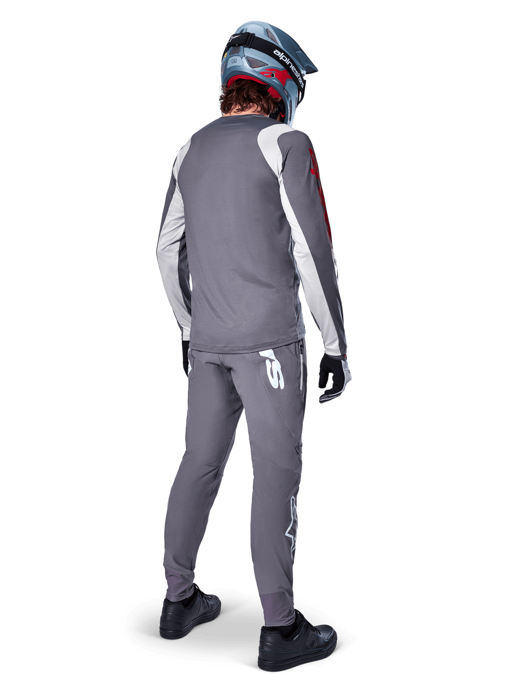 Alpinestars A-Supra Astar Jersey, koszulka MTB z długim rękawem, ciemnoszara z białymi akcentami na rękawach i czerwonym logo, widok od tyłu na rowerzystę w pasujących szarych spodniach i niebieskim kasku full-face, techniczna odzież rowerowa