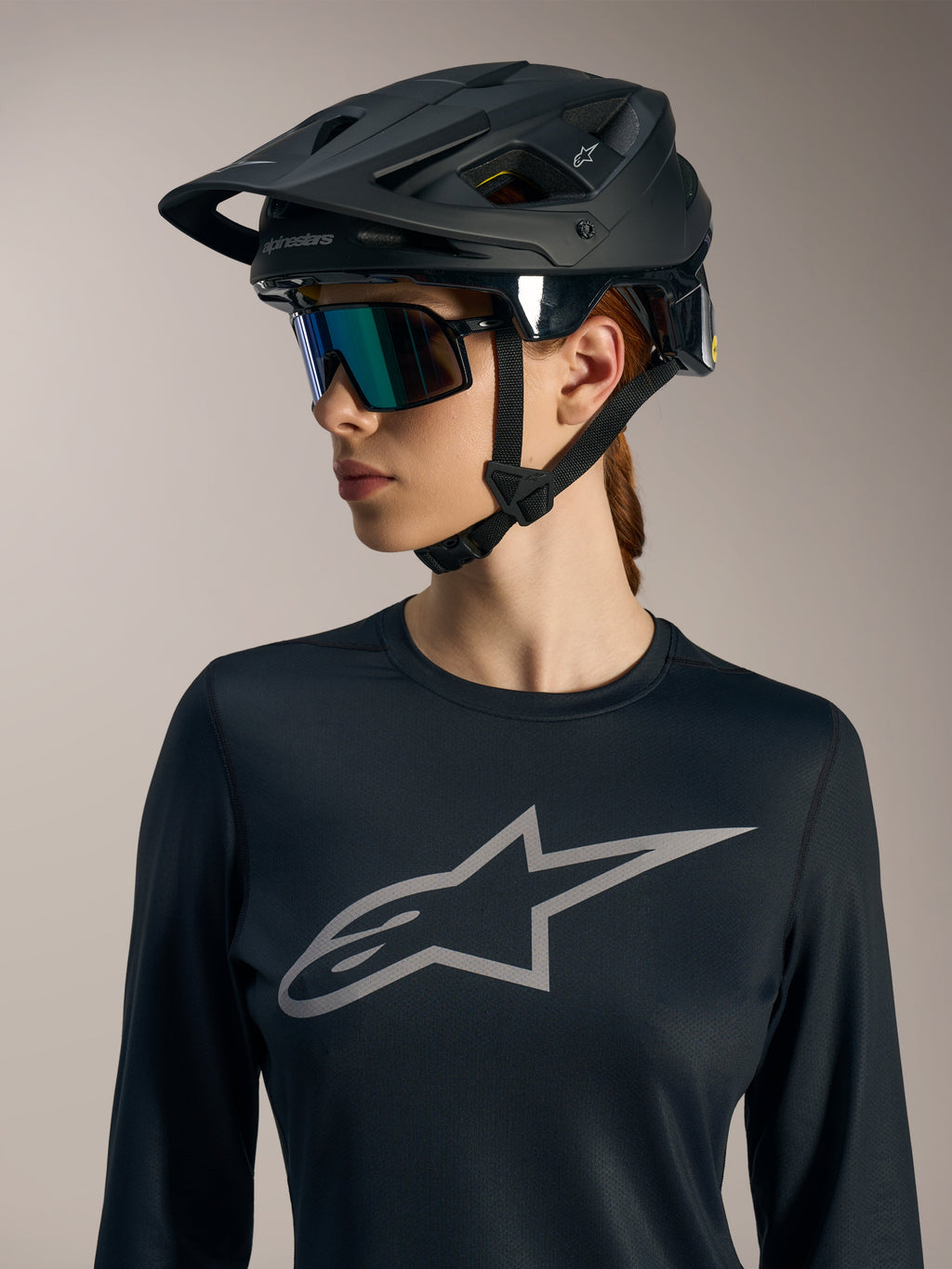 Czarna damska koszulka Stella A-Dura Ride LS z szarym logo Astars, zestawiona z matowym czarnym kaskiem MTB.