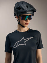 Damska koszulka Alpinestars Stella A-Dura Ride, czarna z szarym logo, kask MTB i okulary przeciwsłoneczne.