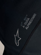 Czarna koszulka Stella A-Dura Ride, zbliżenie na białe logo Alpinestars i branding A-DURA na tkaninie żakardowej.