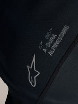 Czarna koszulka Stella A-Dura Ride, zbliżenie na białe logo Alpinestars i branding A-DURA na tkaninie żakardowej.