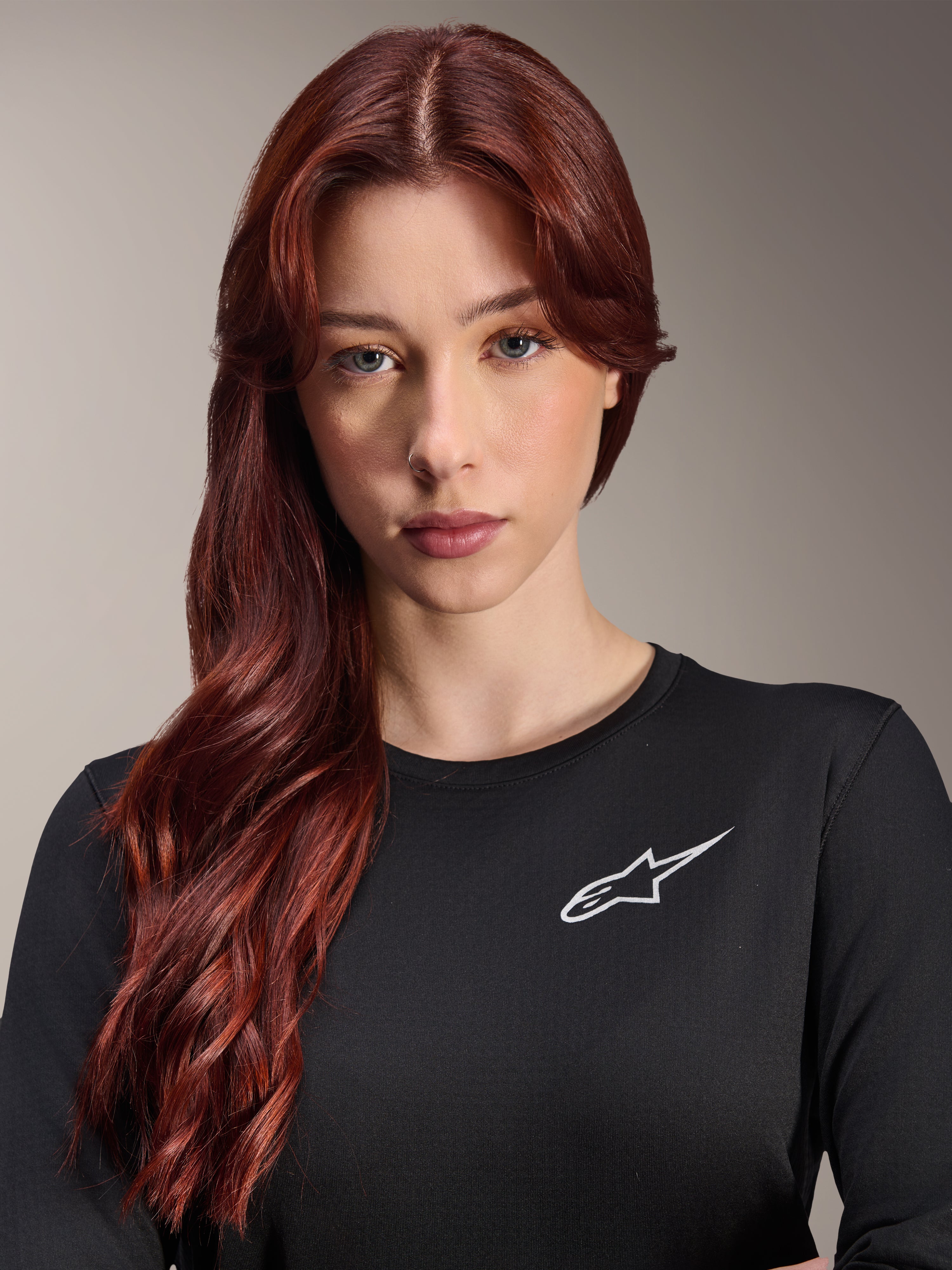 Alpinestars Stella A-Dura Thermal Jersey, damska koszulka MTB z długim rękawem, czarna z białym logo A-star na piersi, zbliżenie na portret kobiety z długimi rudymi włosami, odzież rowerowa na chłodne dni