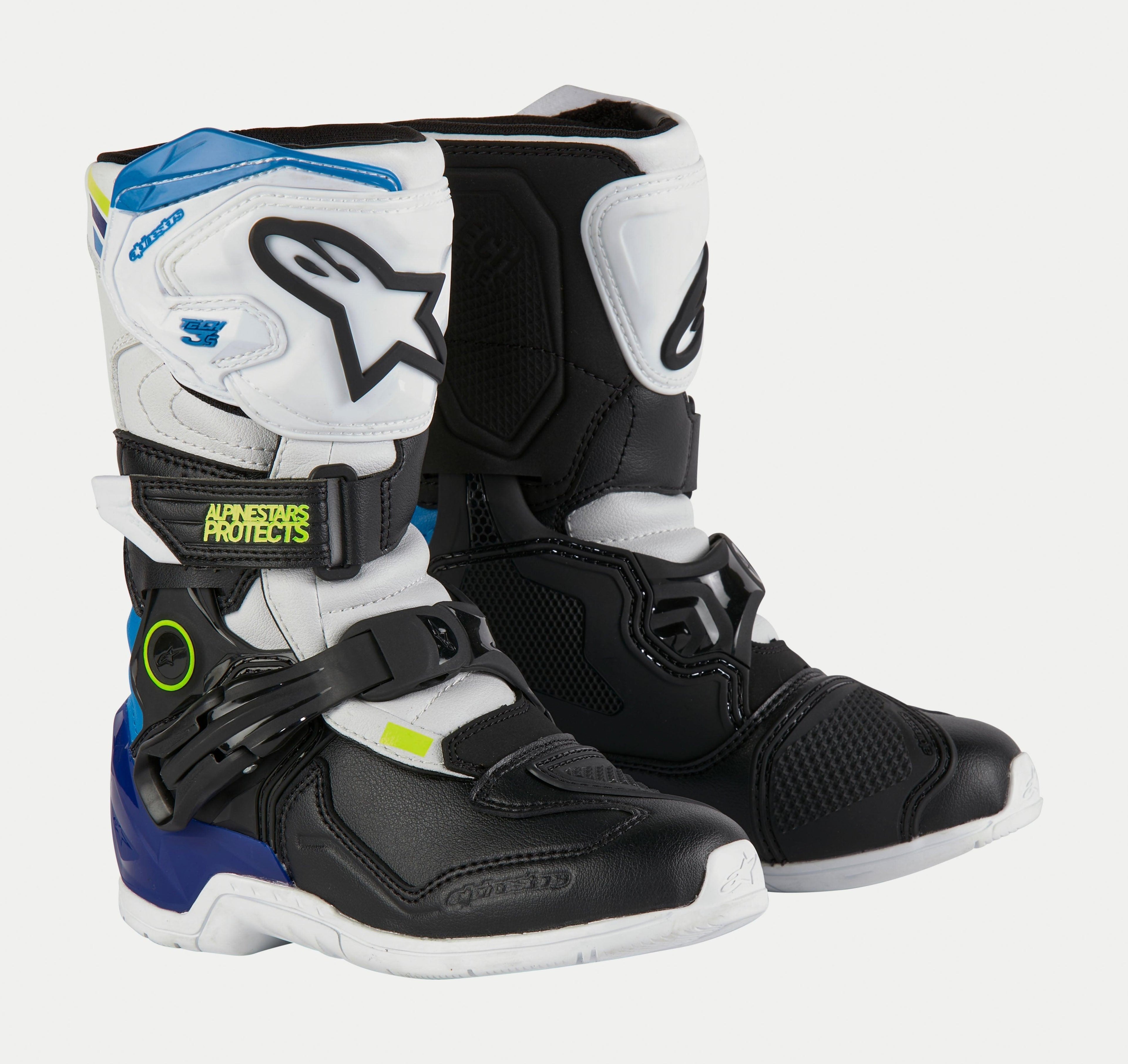 Buty Alpinestars Kids Tech 3S, dziecięce buty motocrossowe, biało-czarno-niebieskie, białe i czarne panele ochronne, niebieskie akcenty na pięcie i u góry, neonowo-żółte logo, bezpieczny system zapięć na klamry