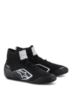 Buty Alpinestars Supertech, buty wyścigowe, czarne, w pełni dzianinowa ognioodporna cholewka i karbonowy zapiętek, białe logo Alpinestars z boku, etykiety certyfikacyjne FIA/SFI na języku, profesjonalne obuwie motorsportowe o nowoczesnym designie