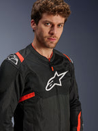 Kurtka Alpinestars T-Sps Air V2, czarna z akcentami Red Fluo, tekstylna siatkowa kurtka motocyklowa prezentowana przez modela, białe logo Alpinestars na klatce piersiowej i ramionach, oddychające panele z siatki, sportowy miejski styl