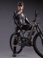Koszulka Alpinestars A-Dura Ride z długim rękawem, czarny kamuflaż, pomarańczowe logo, kolarz na rowerze MTB w studio.
