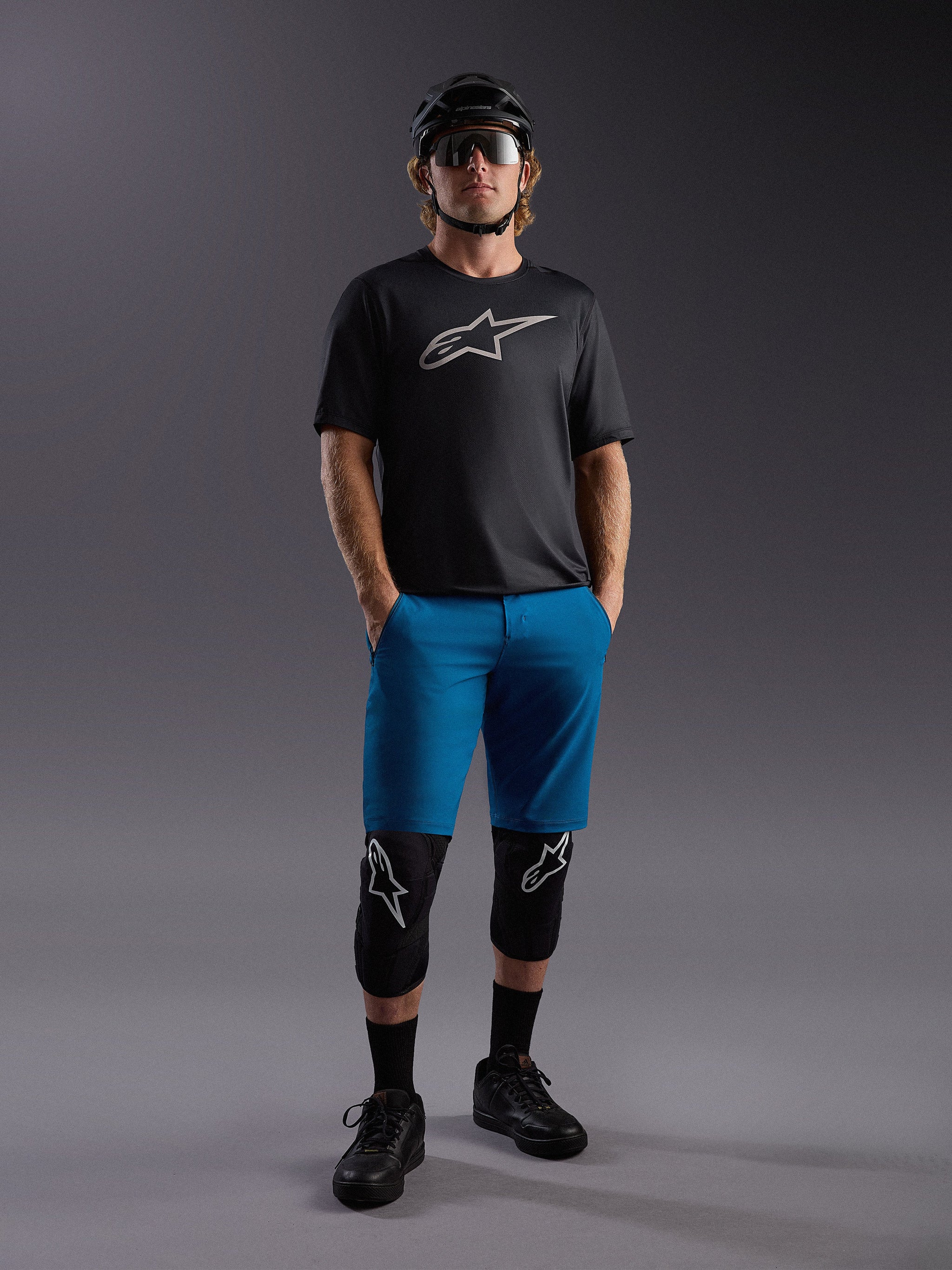 Koszulka Alpinestars A-Dura Ride SS i niebieskie szorty, kompletny strój MTB z ochraniaczami i kaskiem.