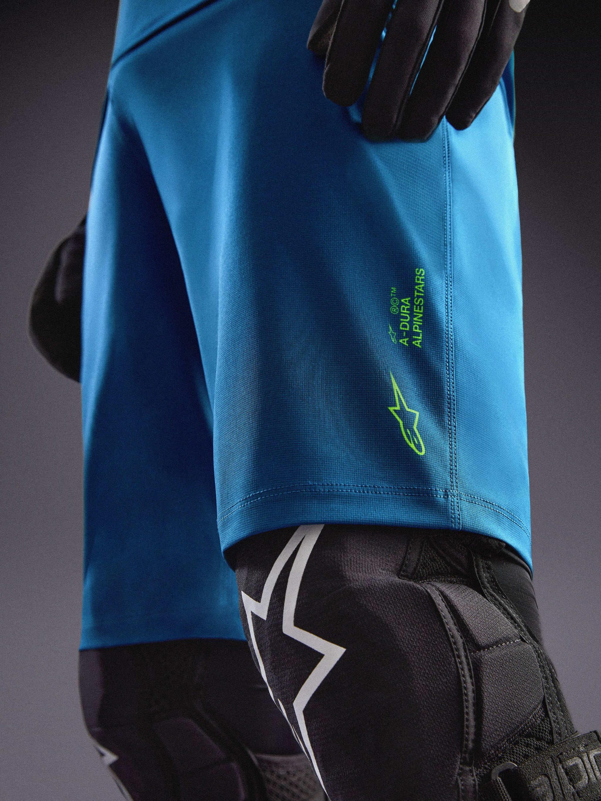 Szorty Alpinestars A-Dura Ride w kolorze niebiesko-zielonym z limonkowym logo i ochraniaczami kolan do MTB.