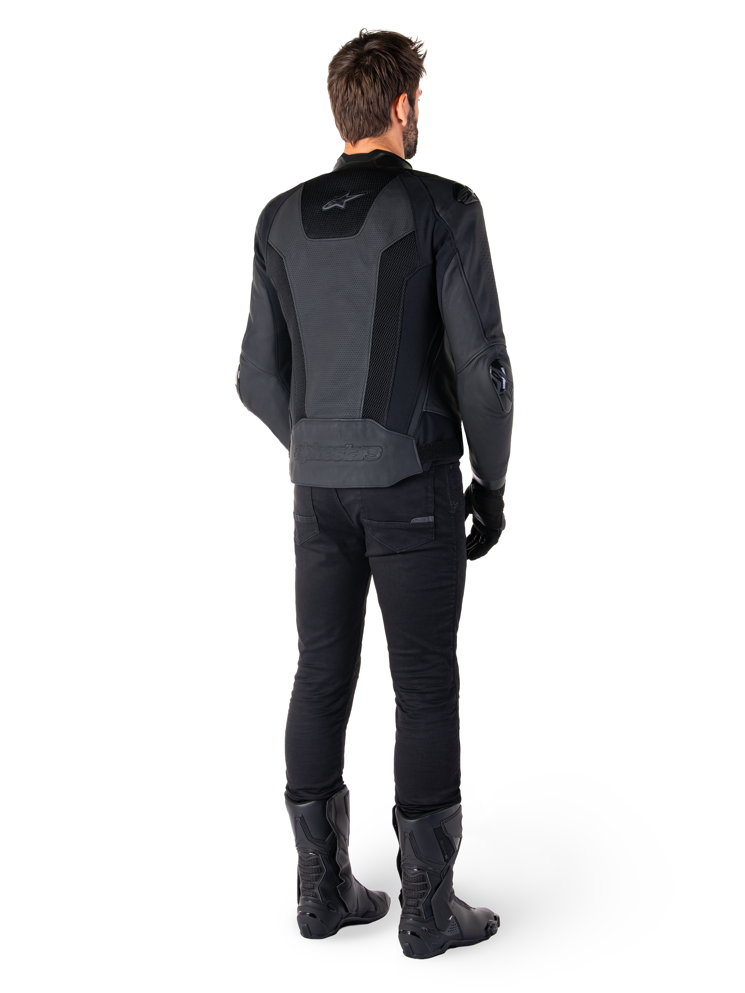 Rear view of a man wearing the Alpinestars Missile V3 Airflow Leather Jacket in Black, featuring extensive perforated panels for ventilation, paired with black riding pants and boots, showcasing a streamlined racing aesthetic.