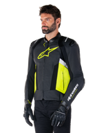 Męski model w skórzanej kurtce Alpinestars Missile V3 Airflow, czarna z żółtymi fluo i białymi akcentami, perforowana skóra dla maksymalnej wentylacji, wyraźne żółte logo na klatce piersiowej, czarne rękawice i spodnie, sportowa odzież motocyklowa
