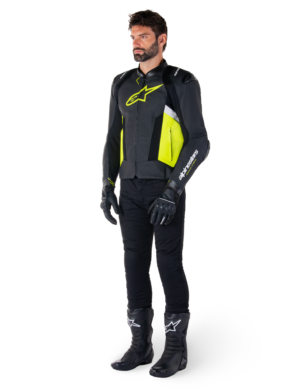 Model ubrany w skórzaną kurtkę Alpinestars Missile V3 Airflow w kolorze czarnym, żółtym fluo i białym, zestawioną z czarnymi rękawicami, spodniami i butami motocyklowymi, prezentujący perforowaną skórzaną konstrukcję i estetykę inspirowaną wyścigami.