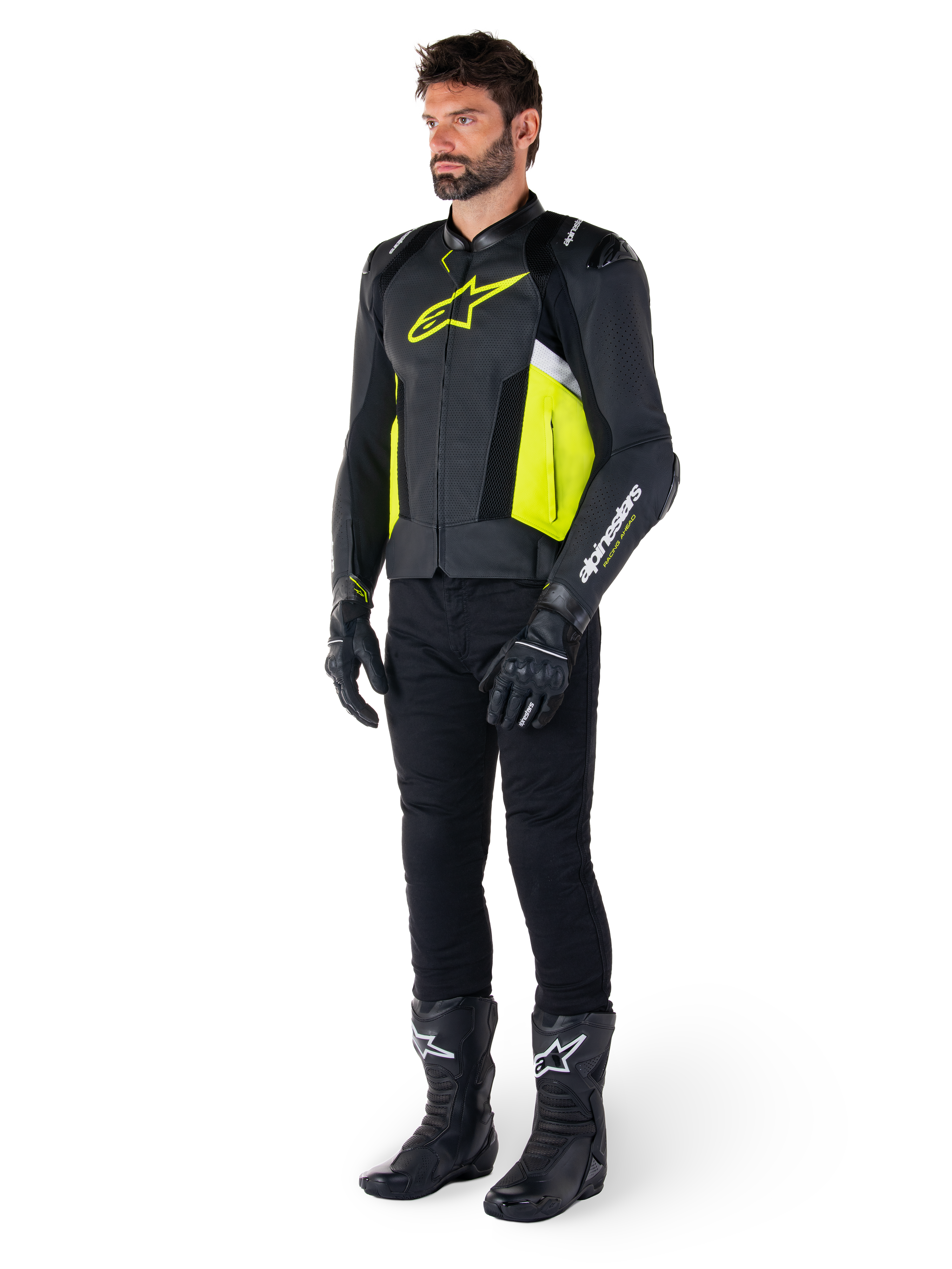 Model ubrany w skórzaną kurtkę Alpinestars Missile V3 Airflow w kolorze czarnym, żółtym fluo i białym, zestawioną z czarnymi rękawicami, spodniami i butami motocyklowymi, prezentujący perforowaną skórzaną konstrukcję i estetykę inspirowaną wyścigami.