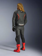Kurtka skórzana Alpinestars GP Force V2, Black Red Fluo, widok z tyłu na motocykliście w dopasowanych czarnych skórzanych spodniach, czerwonych butach wyścigowych i czarnych rękawicach, wyraźne czerwone akcenty, logo Alpinestars na plecach, sportowa odzież motocyklowa