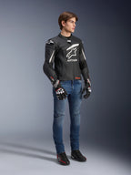 Kurtka skórzana Alpinestars GP Plus R V4 Rideknit, czarno-biała, motocyklowa kurtka skórzana noszona przez modela w niebieskich dżinsach i czarnych rękawicach, z wyraźnym białym logo Astars na klatce piersiowej, perforowanymi panelami i białymi akcentami na ramionach