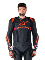 Skórzana kurtka Alpinestars Missile V3 Ignition, wyścigowa kurtka motocyklowa, czarna i czerwona fluo, prezentowana z dopasowanymi rękawicami wyścigowymi i skórzanymi spodniami, z perforowaną wentylacją i widocznym brandingiem Alpinestars, profesjonalna odzież wyścigowa