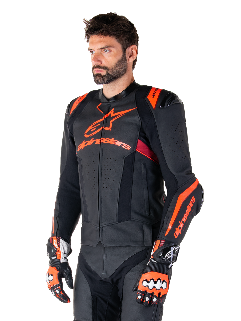 Alpinestars Missile V3 Ignition Leather Jacket, skórzana kurtka motocyklowa, czarna z akcentami w kolorze czerwonym fluo i ciemnoczerwonym, na modelu z pasującymi rękawicami wyścigowymi i skórzanymi spodniami, wyraźne logo Alpinestars, perforowane panele skórzane i zewnętrzne ochraniacze ramion, profesjonalna odzież wyścigowa