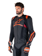 Alpinestars Missile V3 Ignition Leather Jacket, skórzana kurtka motocyklowa, czarna z akcentami w kolorze czerwonym fluo i ciemnoczerwonym, na modelu z pasującymi rękawicami wyścigowymi i skórzanymi spodniami, wyraźne logo Alpinestars, perforowane panele skórzane i zewnętrzne ochraniacze ramion, profesjonalna odzież wyścigowa