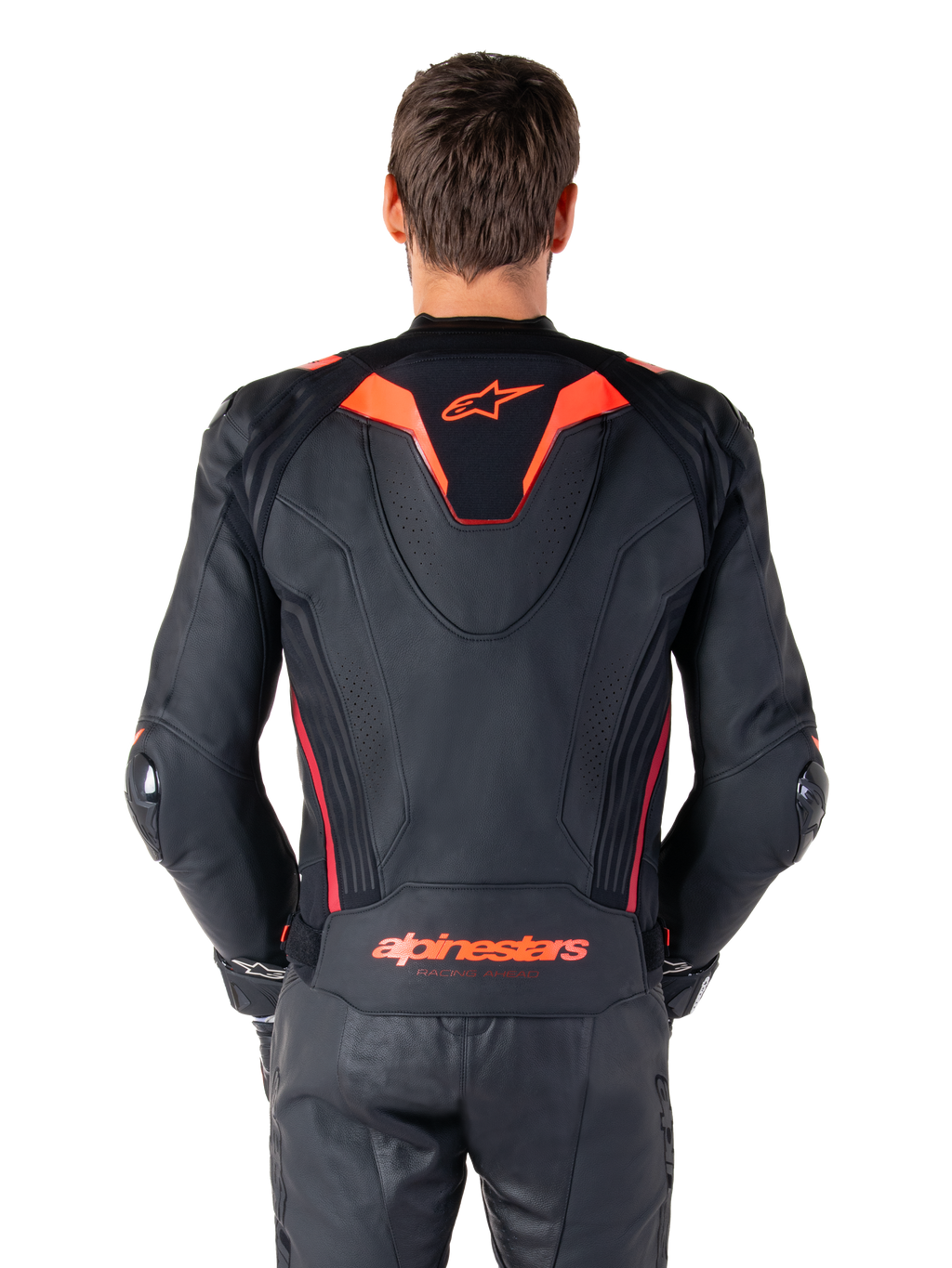 Skórzana kurtka Alpinestars Missile V3 Ignition, widok z tyłu, czarna z akcentami w kolorze fluo czerwonym i ciemnoczerwonym, sportowy garb aerodynamiczny, logo Alpinestars na plecach, noszona z dopasowanymi czarnymi skórzanymi spodniami motocyklowymi, profesjonalna odzież wyścigowa