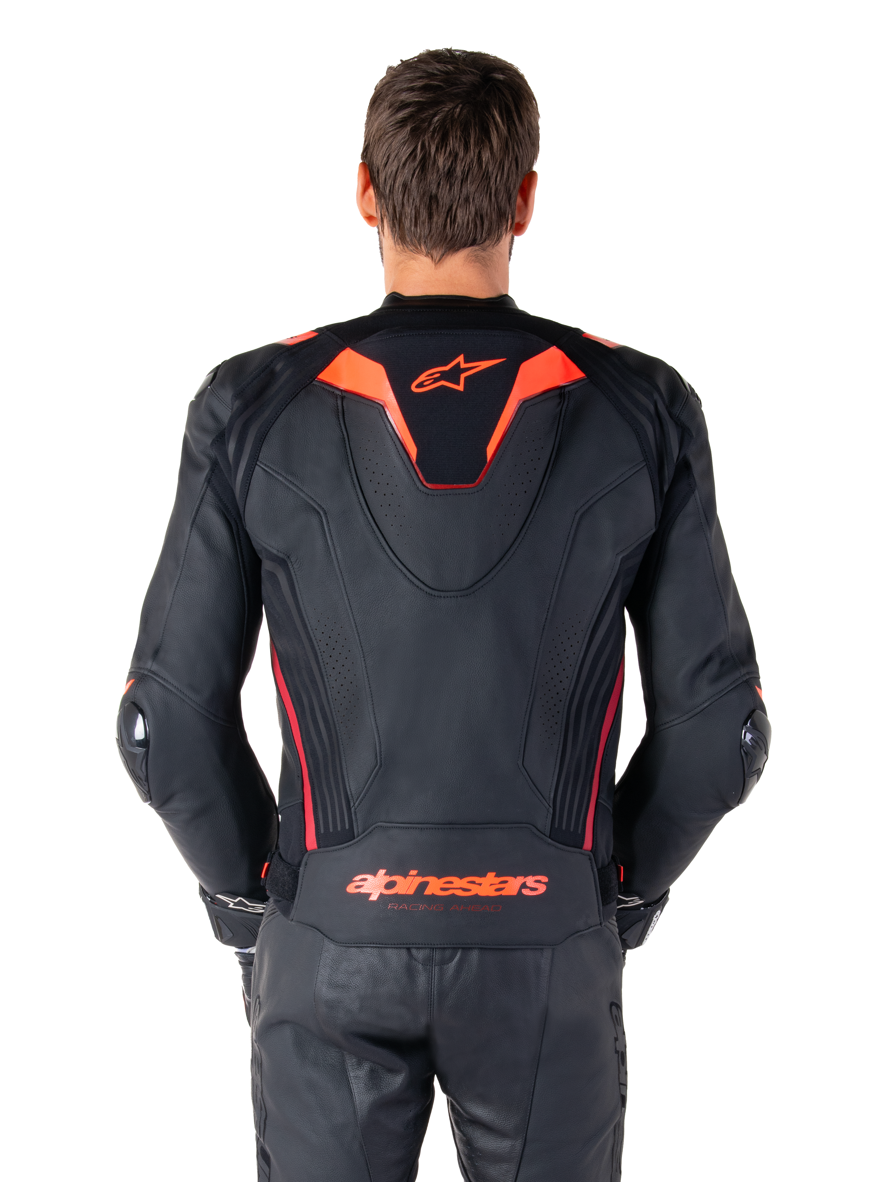 Skórzana kurtka Alpinestars Missile V3 Ignition, widok z tyłu, czarna z akcentami w kolorze fluo czerwonym i ciemnoczerwonym, sportowy garb aerodynamiczny, logo Alpinestars na plecach, noszona z dopasowanymi czarnymi skórzanymi spodniami motocyklowymi, profesjonalna odzież wyścigowa