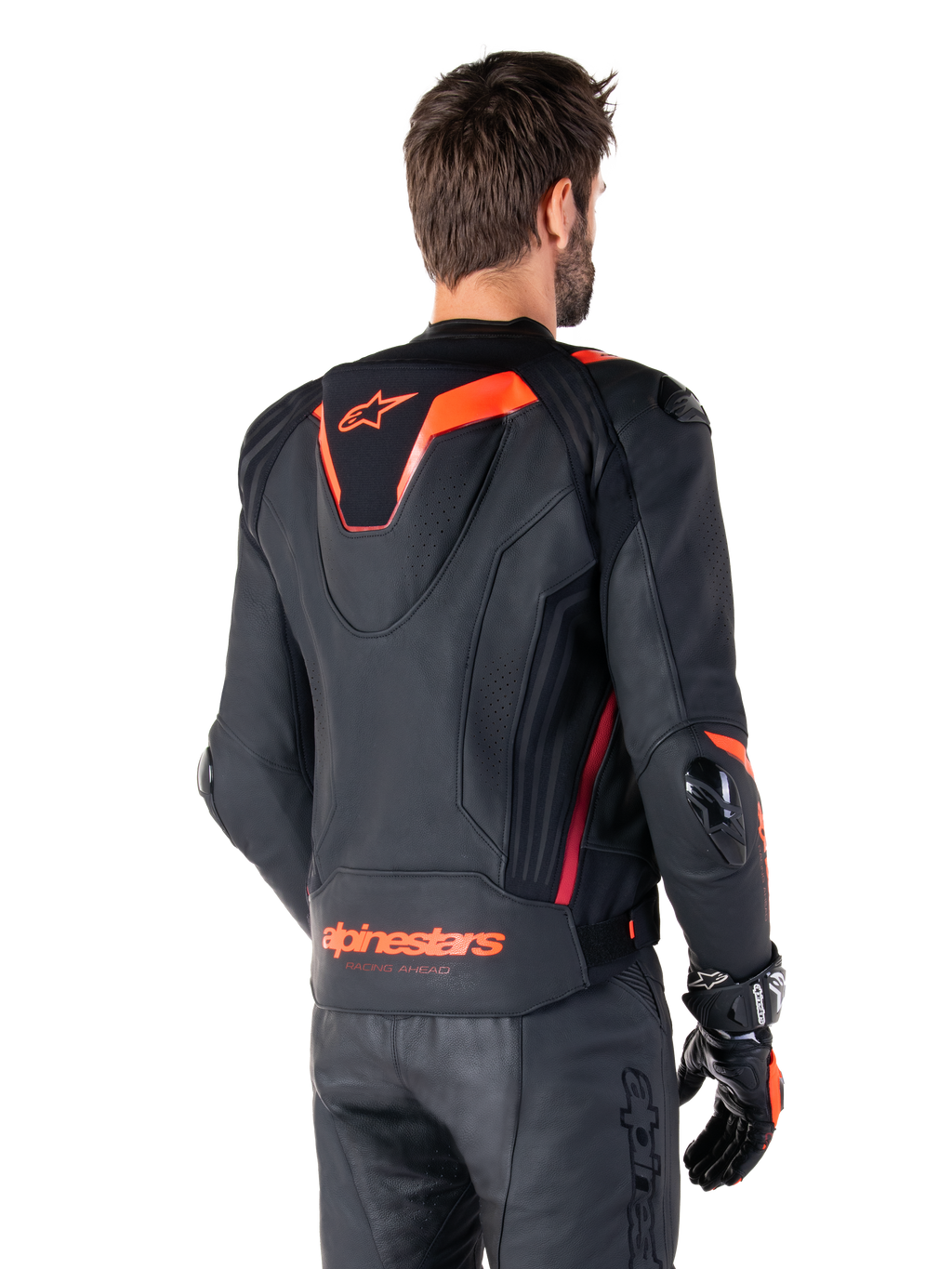 Skórzana kurtka Alpinestars Missile V3 Ignition, męska sportowa kurtka wyścigowa, czarna z akcentami Red Fluo, widok z tyłu prezentujący smukły aerodynamiczny garb i logo Alpinestars na dole pleców, noszona z czarnymi skórzanymi spodniami i rękawicami wyścigowymi, profesjonalny design sportowy