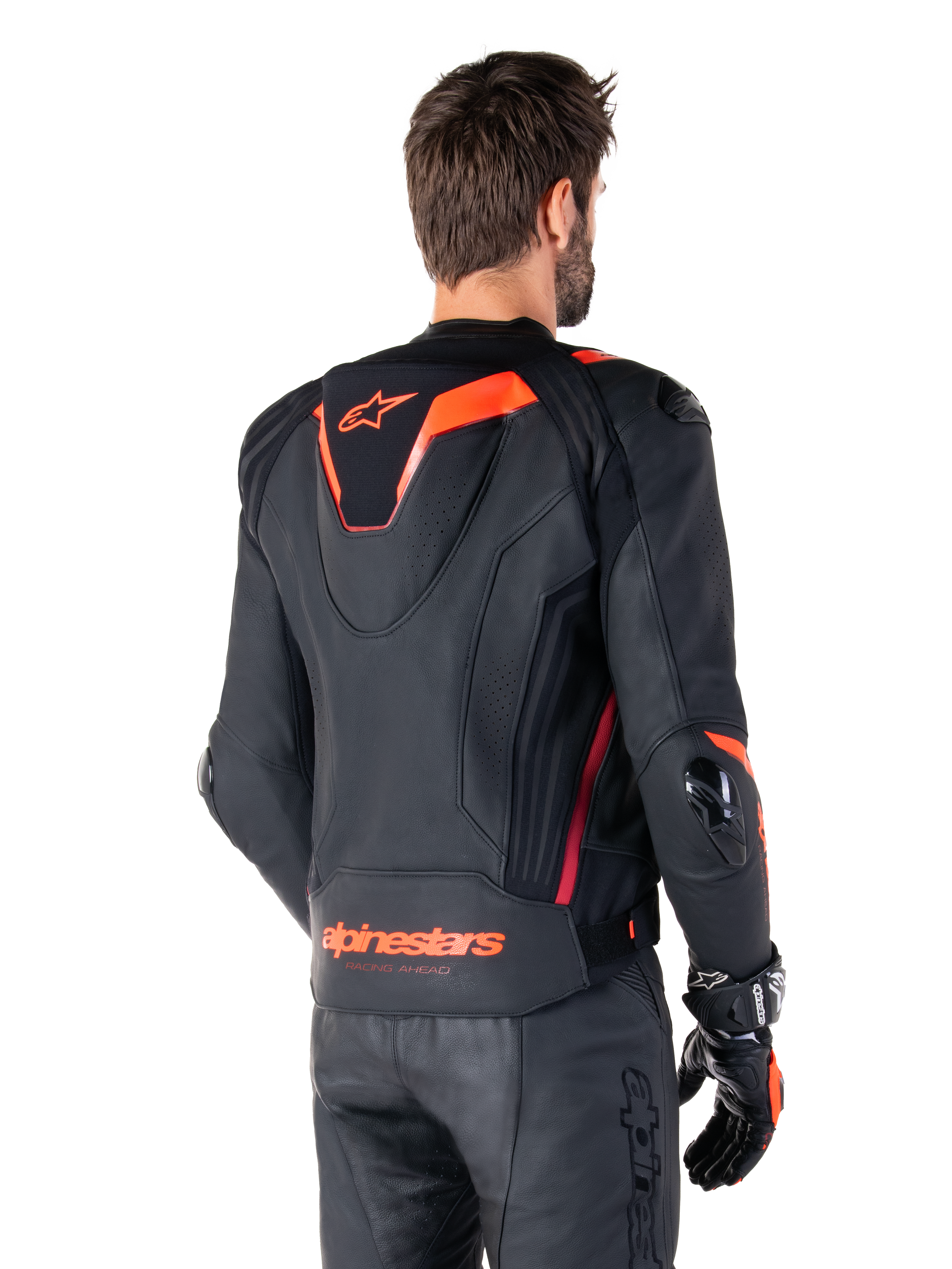 Skórzana kurtka Alpinestars Missile V3 Ignition, męska sportowa kurtka wyścigowa, czarna z akcentami Red Fluo, widok z tyłu prezentujący smukły aerodynamiczny garb i logo Alpinestars na dole pleców, noszona z czarnymi skórzanymi spodniami i rękawicami wyścigowymi, profesjonalny design sportowy