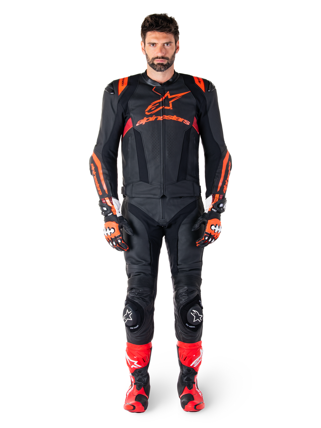 Męski model mający na sobie skórzaną kurtkę Alpinestars Missile V3 Ignition w kolorze Black Red Fluo Dark Red, kompletny motocyklowy strój wyścigowy, w tym pasujące skórzane spodnie, rękawice wyścigowe i buty, z wyraźnym brandingiem Alpinestars na klatce piersiowej, poza przodem, profesjonalny sportowy strój motocyklowy