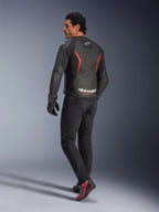 Męski model widoczny od tyłu w kurtce skórzanej Alpinestars GP Force V2 Air w kolorze Black Red Fluo, z licznymi perforacjami na plecach i wyraźnym białym brandingiem, zestawionej z czarnymi spodniami motocyklowymi, rękawicami i czarno-czerwonymi butami motocyklowymi, tło studyjne