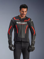 Skórzana kurtka motocyklowa Alpinestars GP Force V2 Air, kurtka wyścigowa, czarna i czerwona fluo, konstrukcja ze skóry premium z licznymi perforacjami zapewniającymi przepływ powietrza, noszona przez modela w czarnych rękawicach i spodniach, z wyraźnym brandingiem i napisem „Racing Ahead” na klatce piersiowej