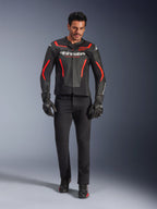 Motocyklista w skórzanej kurtce Alpinestars GP Force V2 Air, czarno-czerwona Fluo, zestawiona z czarnymi jeansami, rękawicami i butami, perforowana skórzana konstrukcja, białe logo i sportowe czerwone akcenty