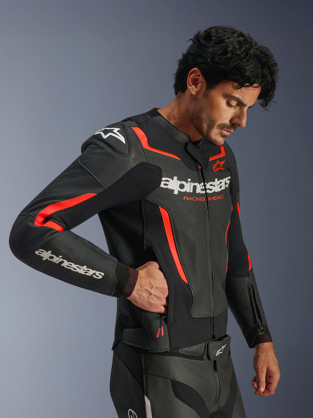 Alpinestars GP Force V2 Air Leather Jacket, czarno-czerwona (Fluo), perforowana skórzana kurtka motocyklowa, model w kurtce sięgający do bocznej kieszeni zapinanej na zamek, z fluorescencyjnymi czerwonymi akcentami i białym logo Alpinestars, profesjonalna sportowa odzież motocyklowa.