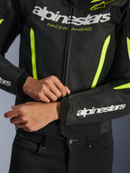 Alpinestars GP Force V2 Air Leather Jacket, czarno-żółta fluo, zbliżenie na konstrukcję z perforowanej skóry i akcenty o wysokiej widoczności, widoczne logo oraz grafika „RACING AHEAD”, sportowy design motocyklowy
