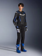 Motocyklista w skórzanej kurtce GP Force V2 Airflow w kolorze Black Metallic Blue, z pasującymi rękawicami wyścigowymi i niebieskimi butami, perforowana skóra i wyraźny branding Alpinestars, profesjonalna odzież motocyklowa