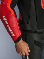 Kurtka skórzana Alpinestars GP Force V2 Air, czerwona i neonowa czerwona, zbliżenie na perforowany skórzany rękaw z wyrazistym białym logo Alpinestars, czarne teksturowane panele, zamek do łączenia ze spodniami w pasie, zaawansowana ochrona sportowa