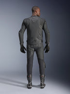 Męski model widoczny od tyłu w skórzanej kurtce Alpinestars Dusk Airflow w kolorze czarnym, w zestawie z dopasowanymi czarnymi skórzanymi spodniami wyścigowymi, rękawicami i butami, z licznymi perforacjami zapewniającymi wentylację oraz logo Alpinestars w dolnej części pleców.