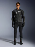 Alpinestars Dusk Airflow Leather Jacket, czarno-biała, motocyklowa kurtka skórzana z perforowanymi panelami dla przepływu powietrza, białe logo Astars na klatce piersiowej, noszona przez motocyklistę w czarnych spodniach, rękawicach i butach motocyklowych, profesjonalne ujęcie studyjne sportowej odzieży motocyklowej.