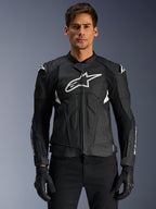 Alpinestars Dusk Airflow Leather Jacket, czarno-biała skórzana kurtka motocyklowa prezentowana na modelu, z perforowanymi panelami skórzanymi dla wentylacji, dużym białym logo na klatce piersiowej i zewnętrznymi sliderami na ramionach.