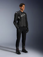 Alpinestars Dusk Airflow Leather Jacket, czarno-biała kurtka skórzana, prezentowana z czarnymi spodniami motocyklowymi, rękawicami i butami, posiada perforowane panele skórzane i białe logo, sportowy styl wyścigowy.