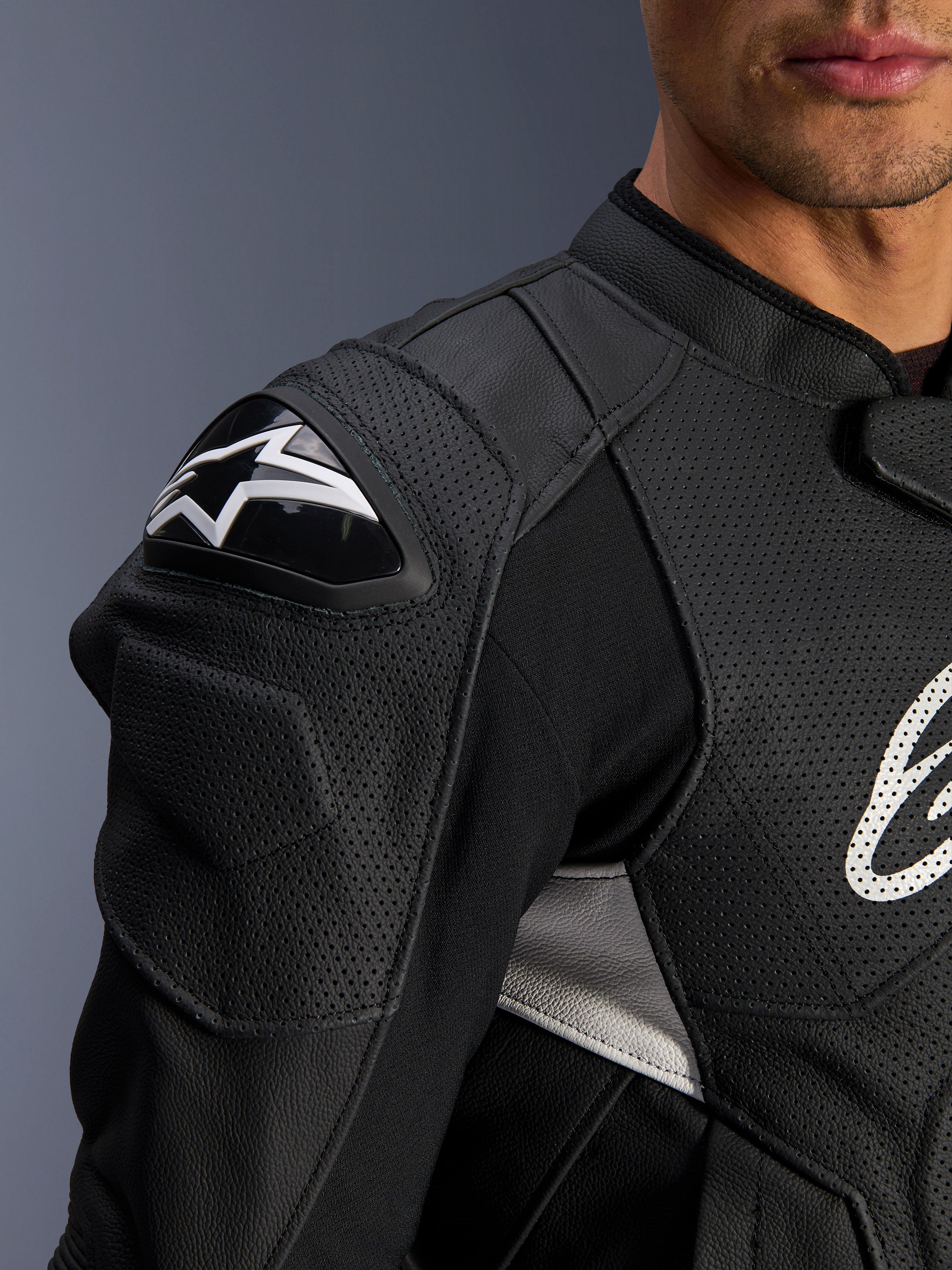 Alpinestars Dusk Airflow Leather Jacket, czarno-biała, zbliżenie na ramię i klatkę piersiową, perforowana skóra zapewniająca wentylację, ochraniacz ramion DFS z białym logo Alpinestars, sportowy design