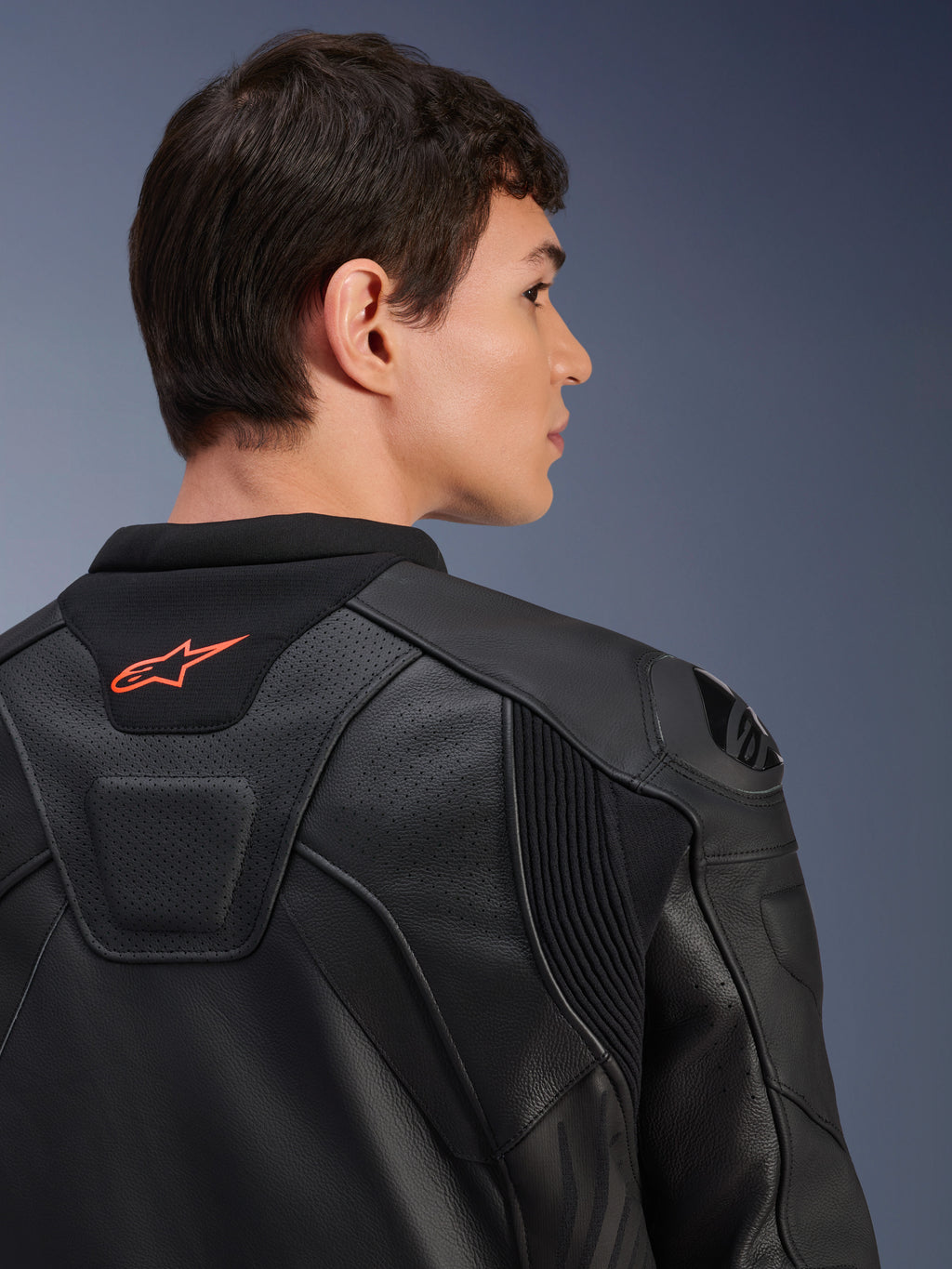 Skórzana kurtka Alpinestars GP Plus R V4 Airflow, czarna, zbliżenie na tył na modelu, widoczna perforowana skóra klasy wyścigowej, techniczne panele elastyczne i małe pomarańczowe logo Alpinestars na kołnierzu, profesjonalna odzież motocyklowa